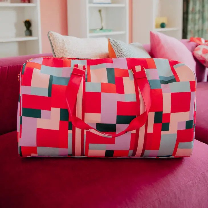 Color Block Weekender Bag has a geometric pattern in reds, pinks, and more. Carrying handles or optional crossbody strap.